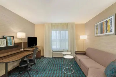 a living room with a couch and a desk in a hotel room at Fairfield Inn & Suites by Marriott Bloomsburg in Bloomsburg