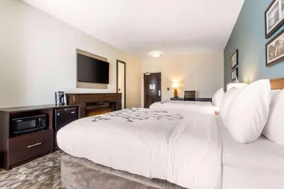 a hotel room with two beds and a flat screen tv at Sleep Inn & Suites Middletown - Goshen in Middletown