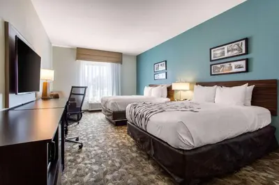 a hotel room with two beds and a flat screen tv at Sleep Inn & Suites Middletown - Goshen in Middletown