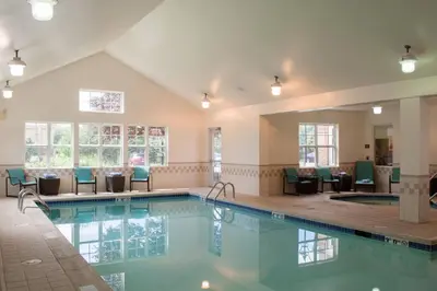 a pool in a hotel with chairs and tables at Residence Inn by Marriott Harrisburg Carlisle in Carlisle