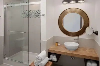 a bathroom with a shower with a sink and a mirror at Watt Hotel Tapestry Collection by Hilton in Rahway