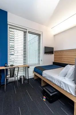 a bedroom with a bed and a desk and a bed and a table at Pod Times Square in New York