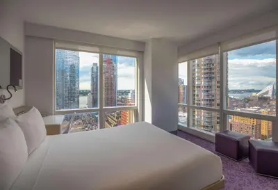 a bedroom with a white bed and large windows at YOTEL New York Times Square in New York