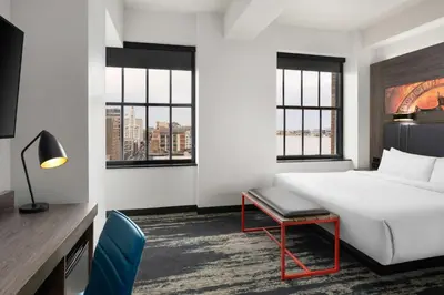 a hotel room with a bed and a desk and windows at Aloft Philadelphia Downtown in Philadelphia