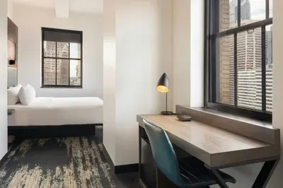 a bedroom with a desk and a bed and a window at Aloft Philadelphia Downtown in Philadelphia