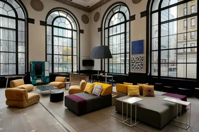 a living room with couches and chairs and windows at Aloft Philadelphia Downtown in Philadelphia