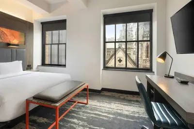 a hotel room with a bed and a desk and windows at Aloft Philadelphia Downtown in Philadelphia