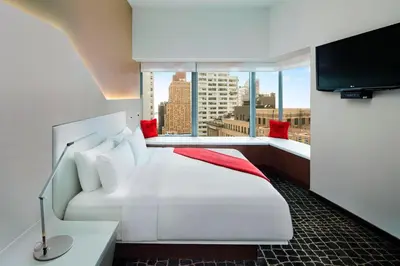a hotel room with a large white bed and a window at The Washington Hotel NYC in New York