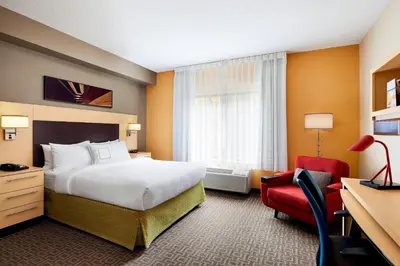 a hotel room with a bed and a red chair at TownePlace Suites by Marriott Harrisburg Hershey in Harrisburg