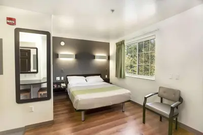 a bedroom with a bed and a mirror and a chair at Studio 6-East Brunswick, NJ - NYC Area in East Brunswick