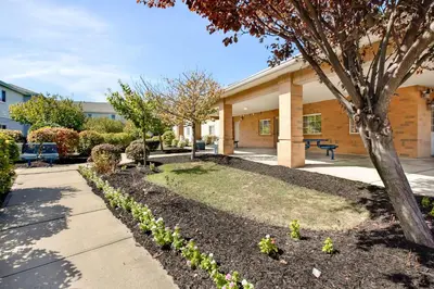 a building with a tree next to a sidewalk at Studio 6-East Brunswick, NJ - NYC Area in East Brunswick