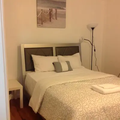 a bedroom with a bed with white sheets and a lamp at Mojoy Homesuites At Runyon in Newark