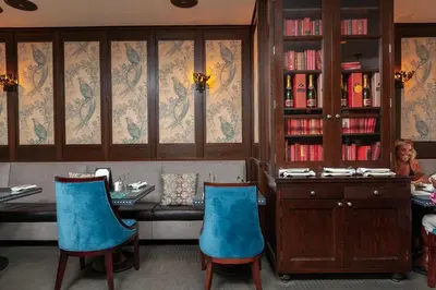 a woman sitting at a table with blue chairs at Fitzpatrick Manhattan in New York