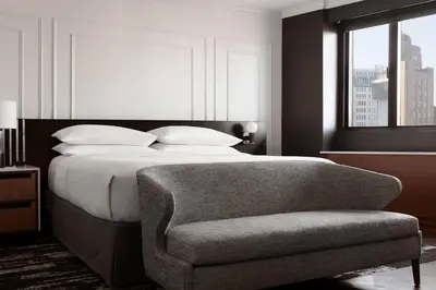 a bedroom with a bed with a chair and a window at New York Marriott Downtown in New York