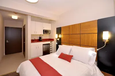 a bedroom with a large white bed and a kitchen at Hotel Five44 in New York