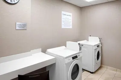 a laundry room with a washing machine and a clock at Courtyard by Marriott Wayne Fairfield in Wayne