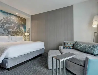 a hotel room with a bed and a couch at Courtyard by Marriott Deptford in Almonesson