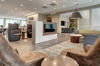 a lobby with chairs and a television in a building at Courtyard by Marriott Deptford in Almonesson