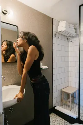 a woman standing in front of a sink in a bathroom at Redford Hotel in New York