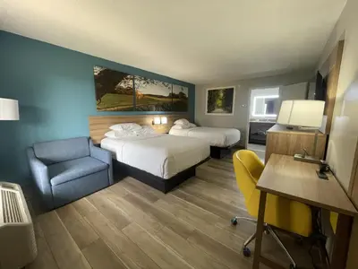 a hotel room with two beds and a desk and a chair at Days Inn & Suites by Wyndham York in York