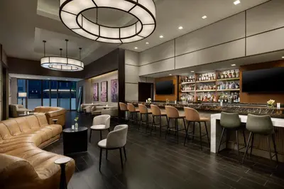 a lobby with a bar with leather furniture and chairs at The Muse New York in New York