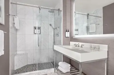 a white bathroom with a shower and a sink at The Muse New York in New York