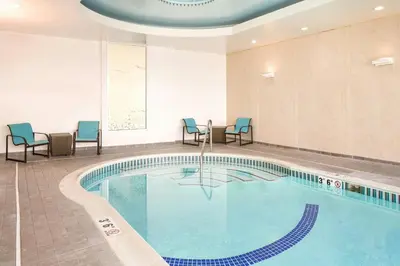 a pool in a hotel room with chairs and tables at SpringHill Suites by Marriott Philadelphia Airport / Ridley Park in Ridley Park