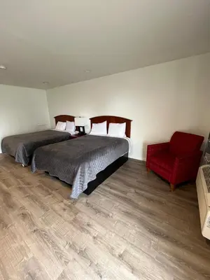 a bedroom with two beds and a red chair at Blue Note Motor Inn in Marietta