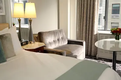a hotel room with a bed and a chair and a window at Loews Regency New York Hotel in New York