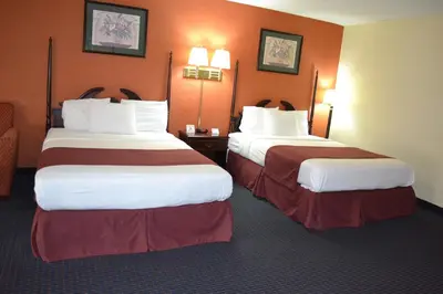 two beds in a hotel room with orange walls at Red Carpet Inn Newark - Irvington NJ in Irvington