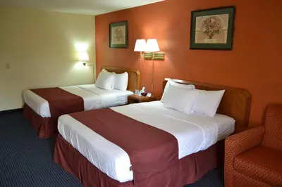a hotel room with two beds and a chair at Red Carpet Inn Newark - Irvington NJ in Irvington
