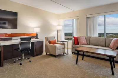 a living room with a couch and a chair and a desk at Delta Hotels by Marriott Philadelphia Airport in Philadelphia