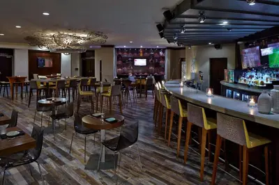 a restaurant with a bar and tables and chairs at Delta Hotels by Marriott Philadelphia Airport in Philadelphia