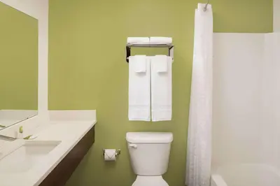 a bathroom with a white toilet and a green wall at WoodSpring Suites South Plainfield in South Plainfield