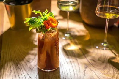 a vase with a plant in it on a table with two glasses at MADE Hotel in New York