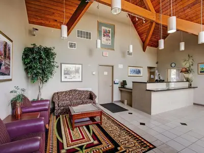 a living room with purple furniture and a kitchen at Red Carpet INN Whippany in Whippany