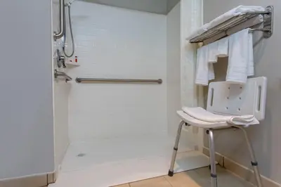 a white shower with a stool in a bathroom at Microtel Inn & Suites by Wyndham Philadelphia Airport in Philadelphia