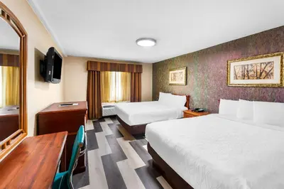a hotel room with two beds and a desk at Rodeway Inn Capri in Little Ferry