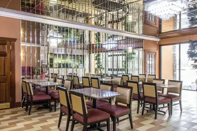 a dining room with tables and chairs and windows at Rodeway Inn Capri in Little Ferry