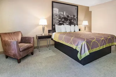 a hotel room with a bed and a chair at Super 8 by Wyndham Mount Laurel in Mount Laurel