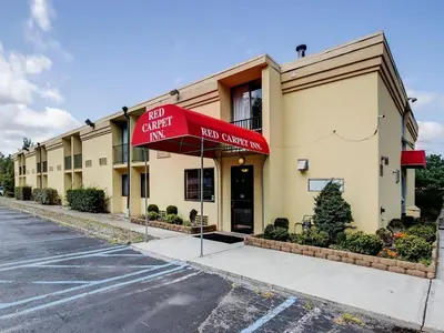 a hotel with a red umbrella in front of a building at Scottish Inn Whippany in Whippany