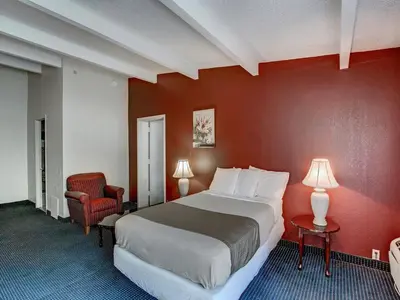 a bedroom with a large bed and a red wall at Scottish Inn Whippany in Whippany