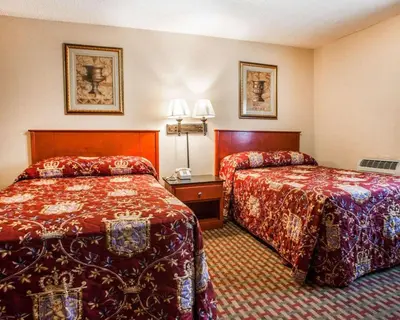 a hotel room with two beds with red sheets at Rodeway Inn Paterson Great Falls Park Area in Paterson