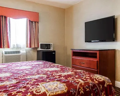 a hotel room with a bed and a flat screen tv at Rodeway Inn Paterson Great Falls Park Area in Paterson
