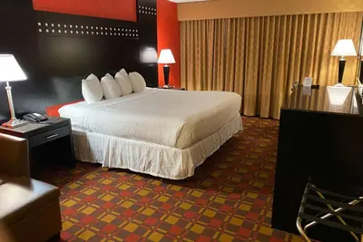a hotel room with a large bed with white sheets at Ramada by Wyndham Rochelle Park Near Paramus in Rochelle Park