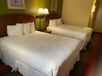 two beds in a hotel room with white sheets at Ramada by Wyndham Rochelle Park Near Paramus in Rochelle Park
