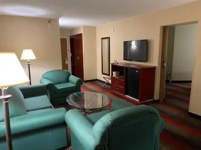a living room with a couch and chairs and a tv at Ramada by Wyndham Rochelle Park Near Paramus in Rochelle Park