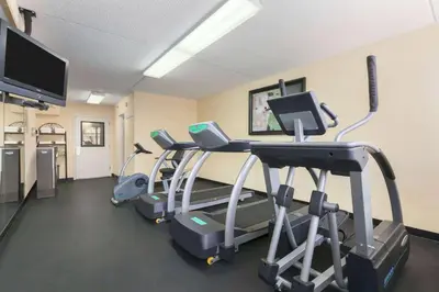 a gym with several tread machines and a flat screen tv at Ramada by Wyndham Rochelle Park Near Paramus in Rochelle Park