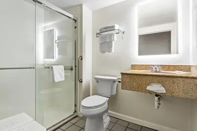 a bathroom with a toilet and a glass shower at Days Inn by Wyndham Lancaster PA Dutch Country in Ronks