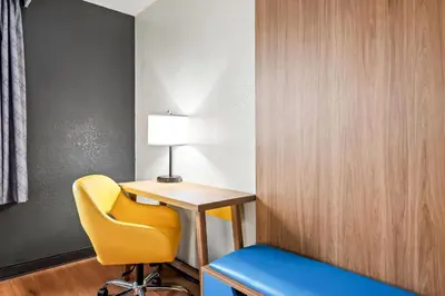 a room with a desk and a yellow chair at Days Inn by Wyndham Lancaster PA Dutch Country in Ronks